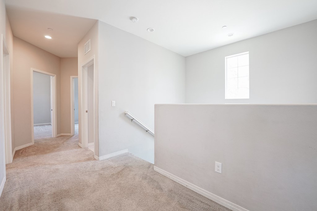 an empty living room with a white wall and a staircase