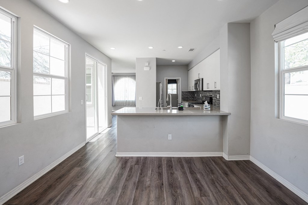 the living room and kitchen of a new home with white walls and wood flooring