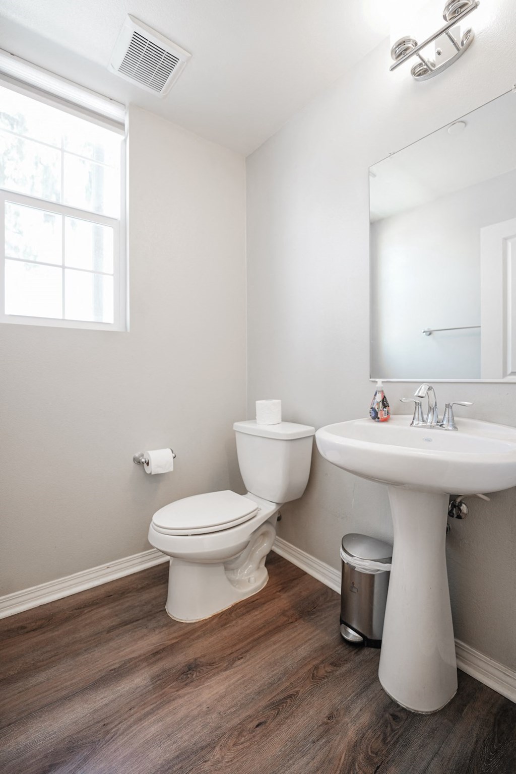 a bathroom with a toilet sink and mirror and a window