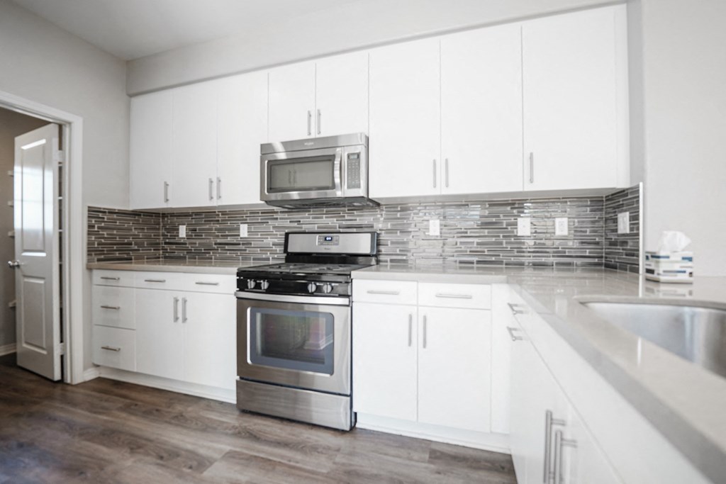 an empty kitchen with white cabinets and stainless steel appliances