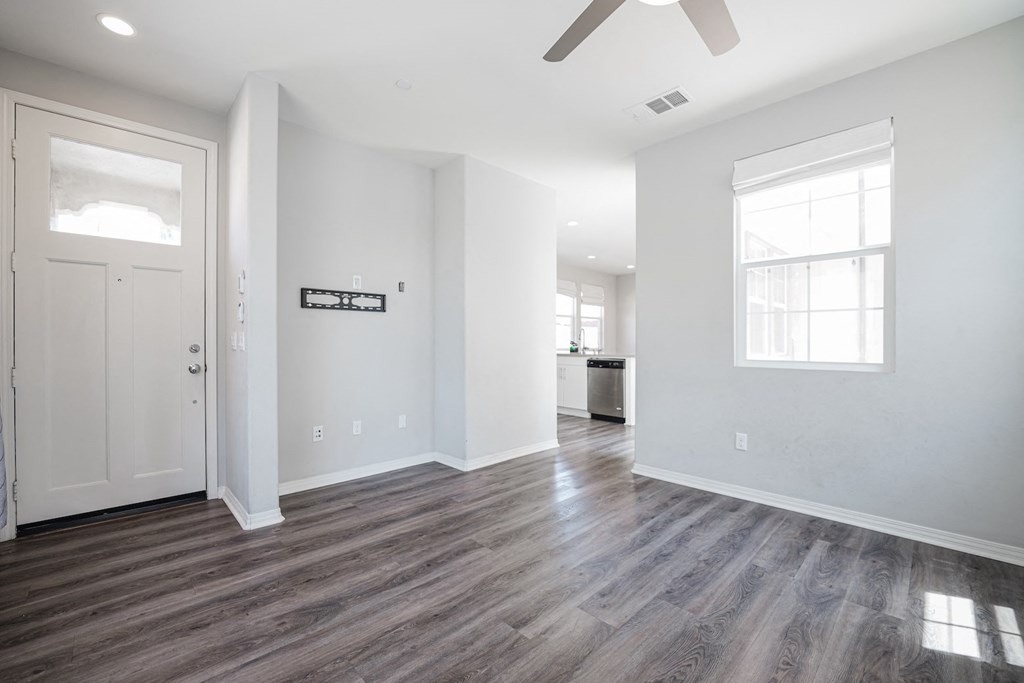 an empty living room with white walls and a ceiling fan