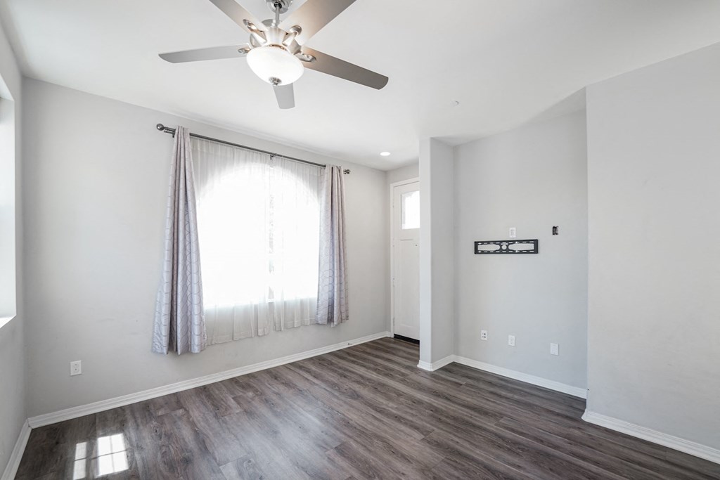 an empty living room with white walls and a ceiling fan