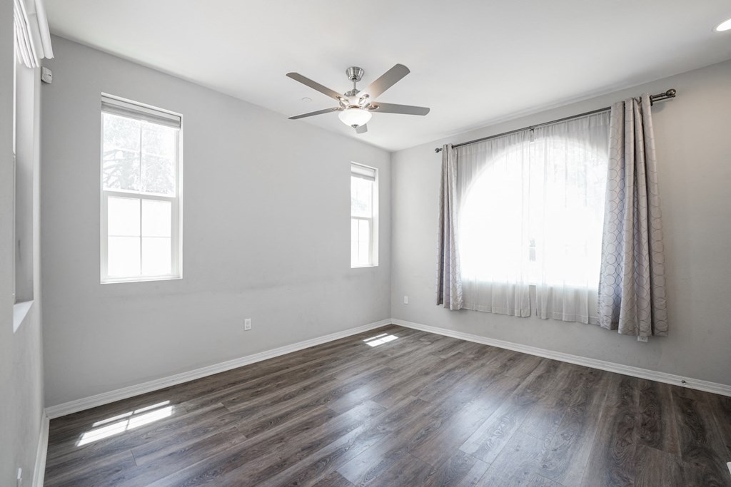 an empty living room with a ceiling fan and a window