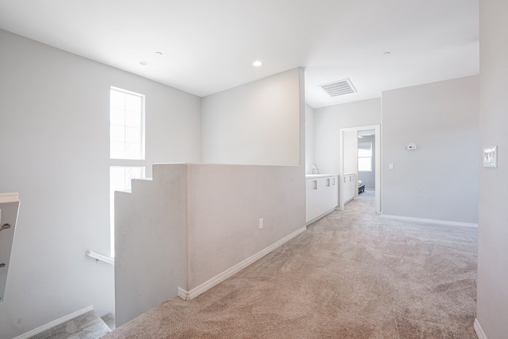 an empty room with a white wall and a carpeted floor