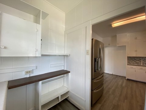 A kitchen with white cabinets and a stainless steel refrigerator.