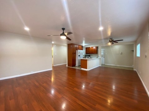 A room with wooden floors and two ceiling fans.