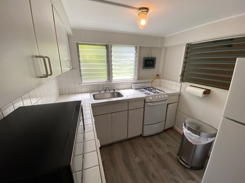 A small, clean kitchen with a black counter top and white cabinets.