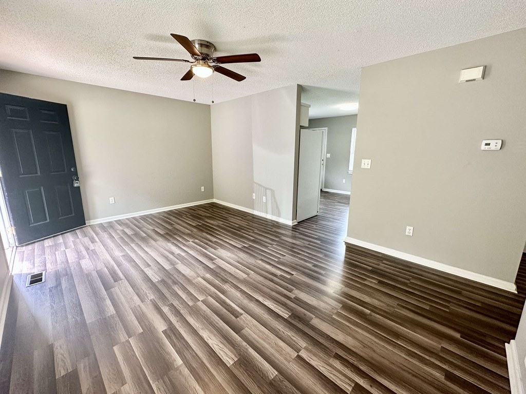 A room with a ceiling fan and wooden flooring.