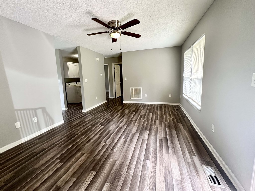 A room with a ceiling fan and wooden flooring.