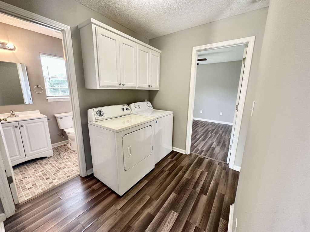 A white kitchen with wood flooring and a white washer and dryer.