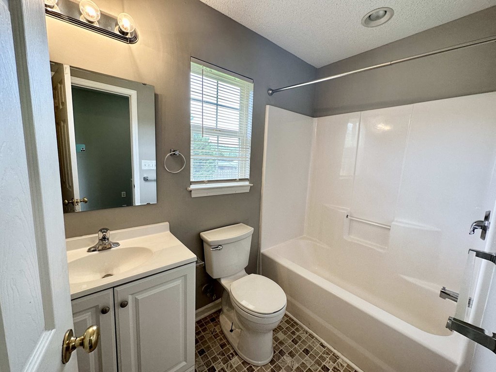 A bathroom with a toilet, sink, and bathtub.