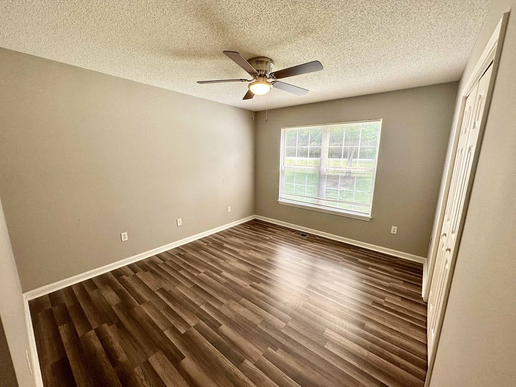 A room with a ceiling fan and wooden flooring.