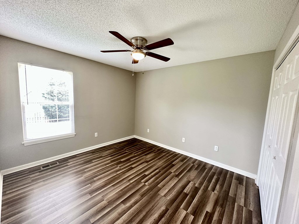 A room with a ceiling fan and wooden flooring.
