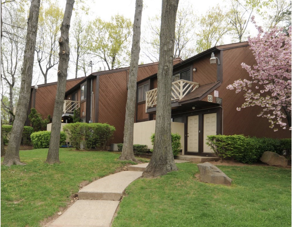 A brown building with a balcony and a tree in front of it.