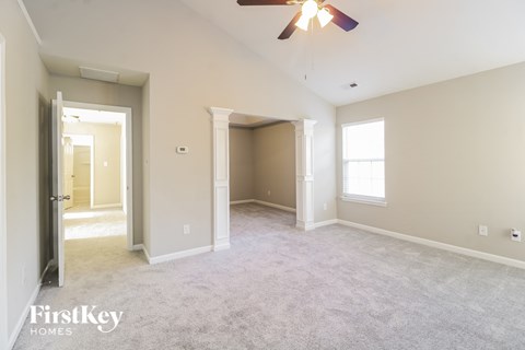a spacious living room with carpet and a ceiling fan