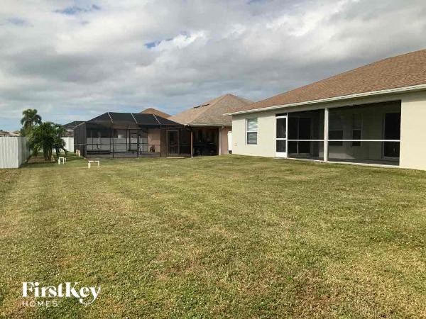 A grassy yard with a house and a fence in the background.