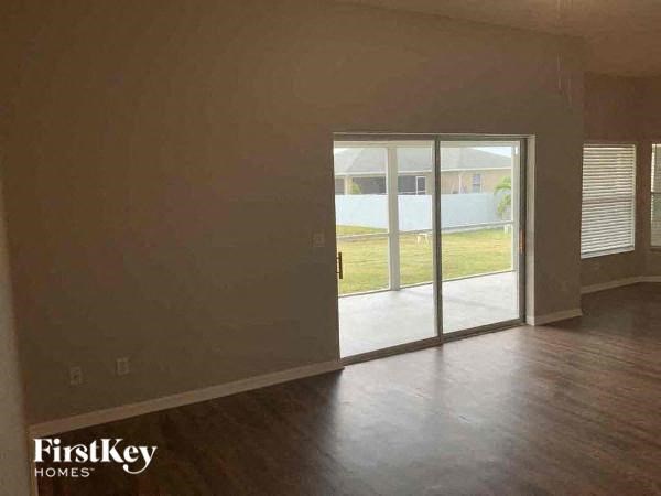 A room with a sliding glass door and wooden flooring.
