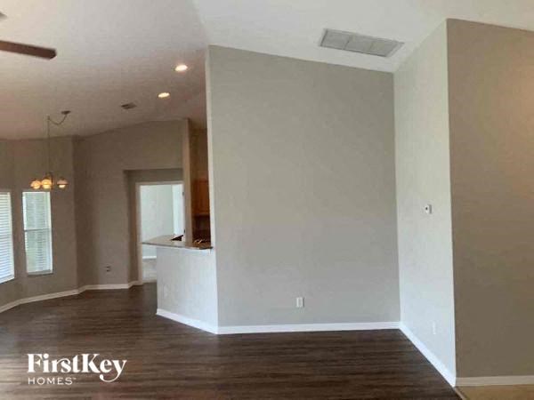 A spacious room with wooden floors and a ceiling fan.