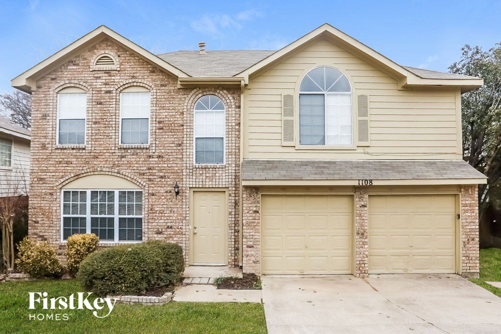 a home with two garage doors and a brick house