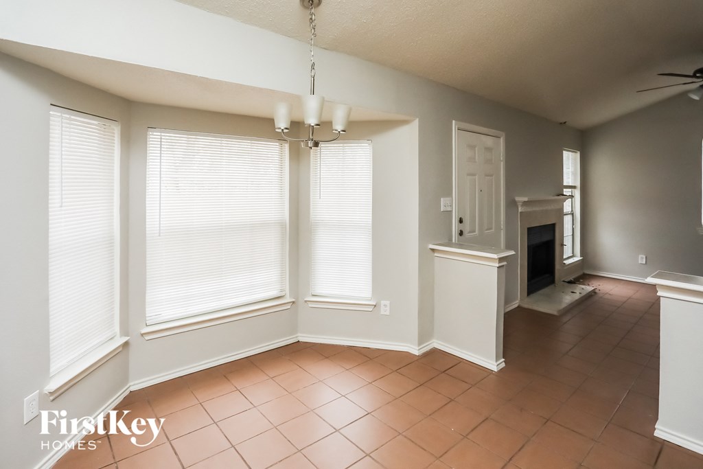 an empty living room with large windows and a fireplace