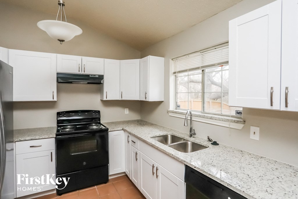 a kitchen with white cabinets and black appliances and a sink