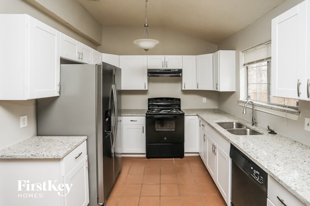 a kitchen with white cabinets and black appliances