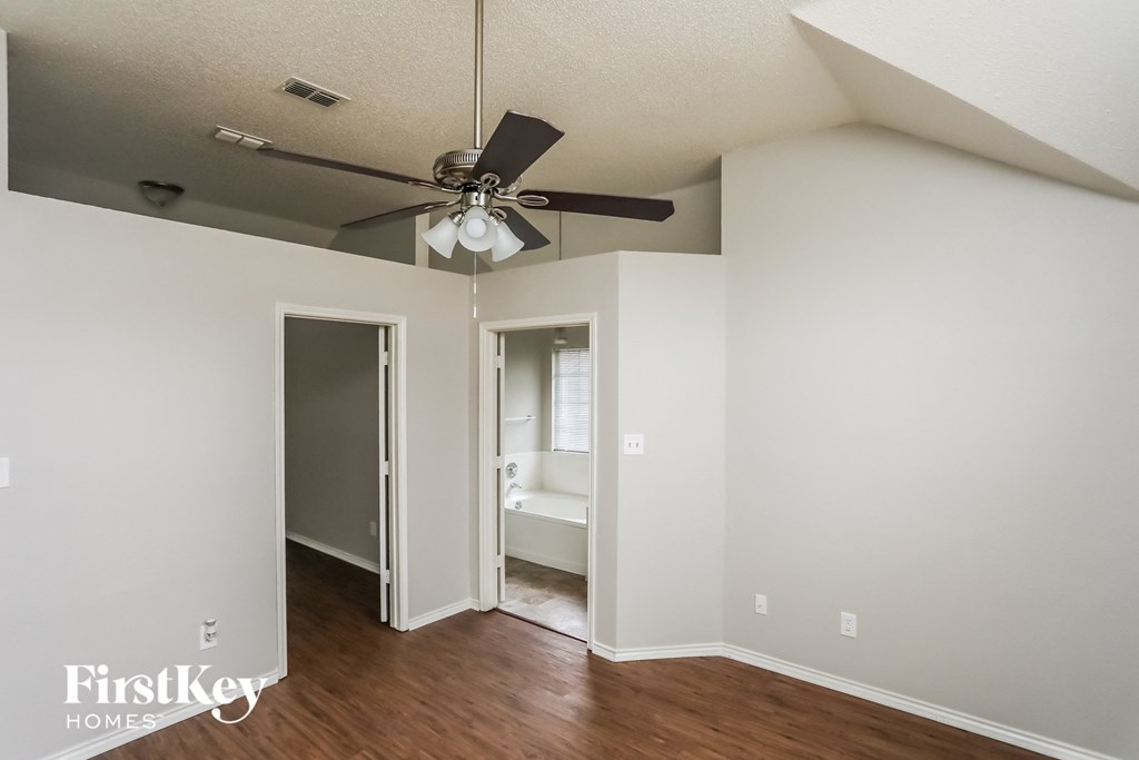a bedroom with a ceiling fan and a door to a bathroom