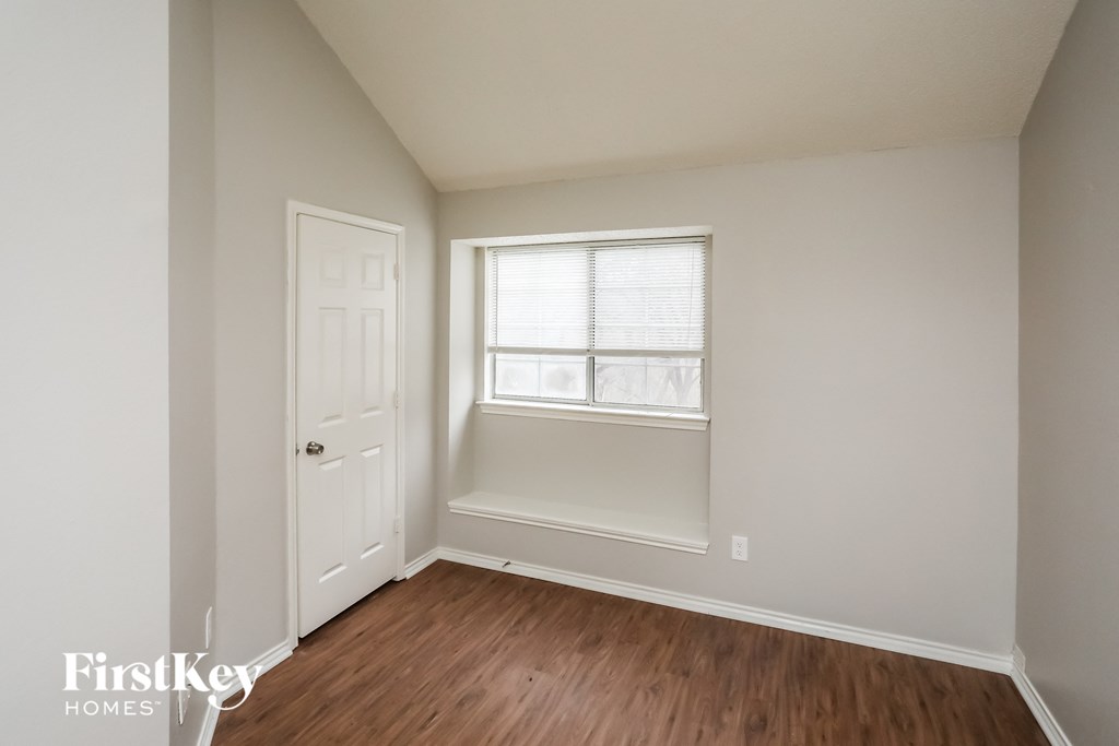a room with a window and a wooden floor and a white door