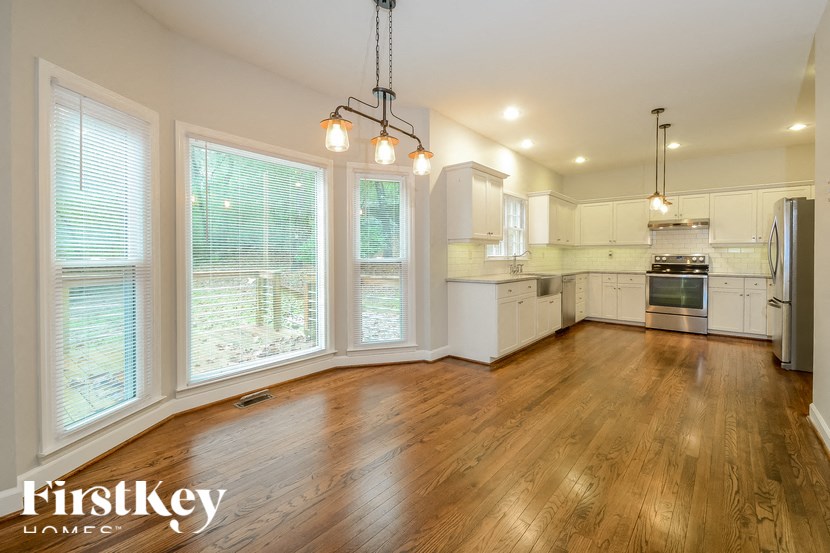 A well-lit kitchen with wooden floors and white cabinetry.