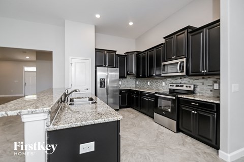 a kitchen with black cabinets and granite counter tops and stainless steel appliances