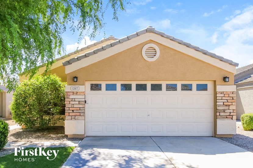 A house with a garage door and a tree in front of it.