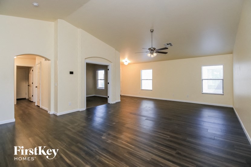 A spacious room with wooden floors and a ceiling fan.