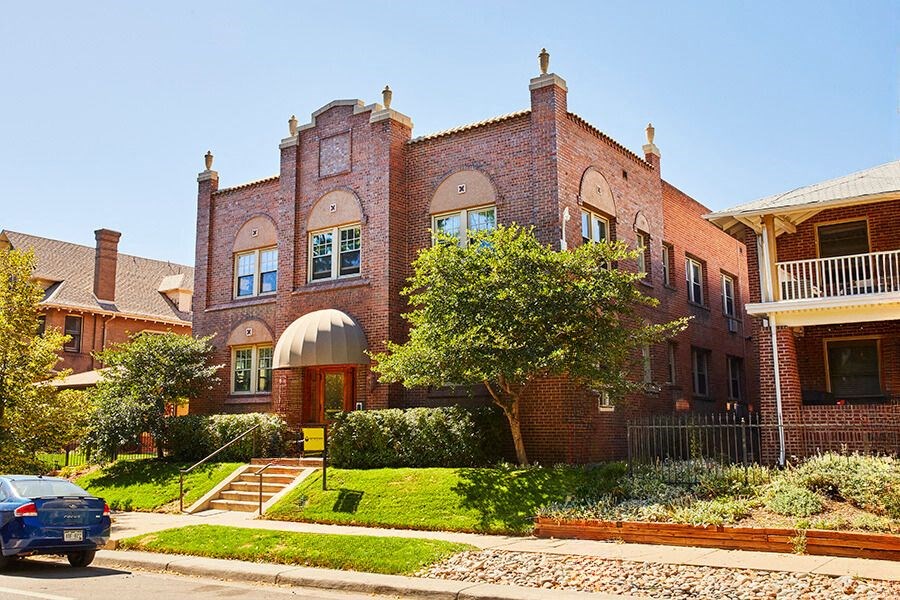 a red brick house with a blue car parked in front of it