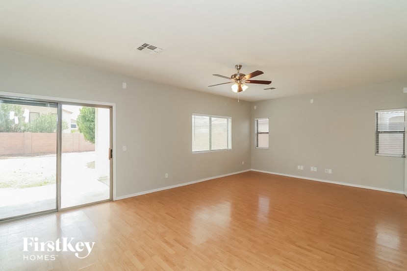 an empty living room with wood floors and a ceiling fan