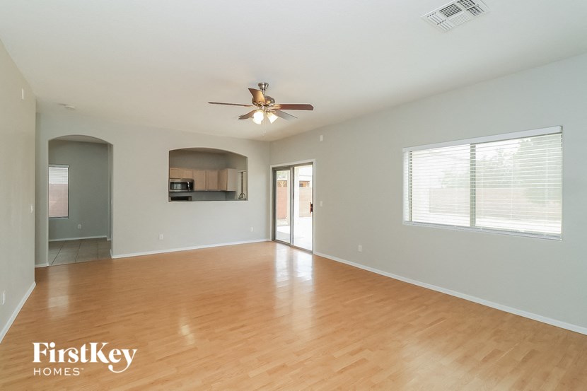 an empty living room with wood flooring and a ceiling fan