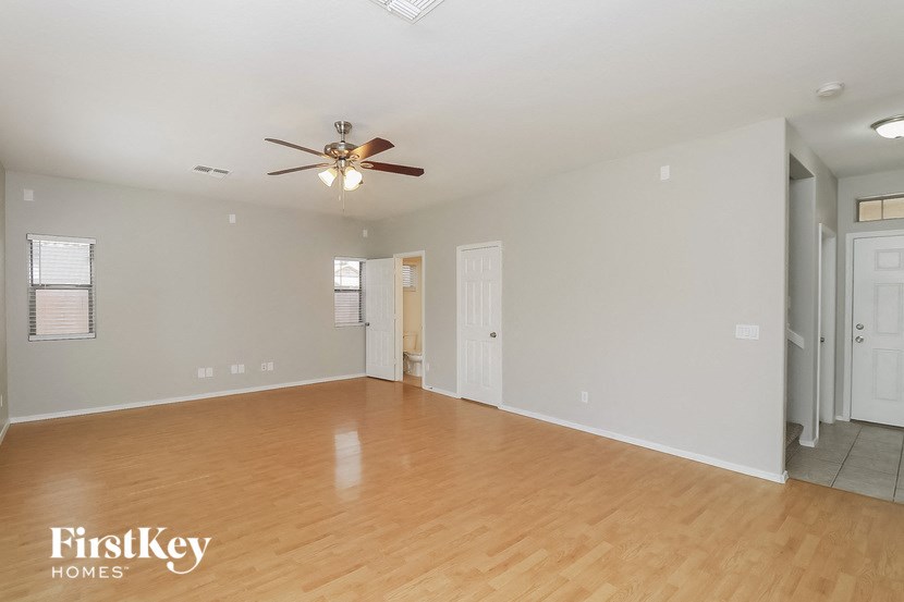 an empty living room with a ceiling fan