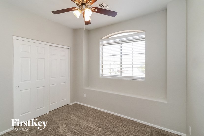an empty bedroom with a ceiling fan and a window
