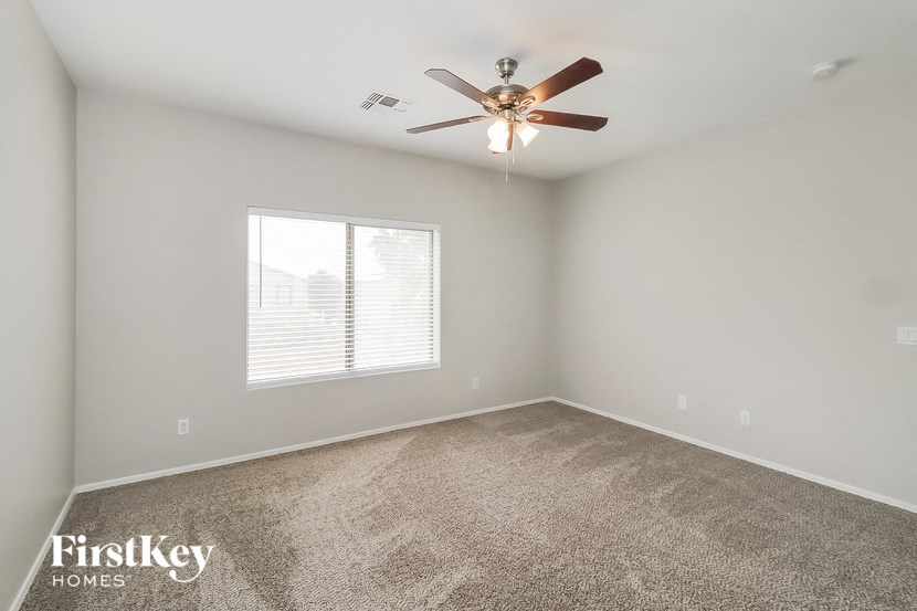 an empty bedroom with a ceiling fan and a window