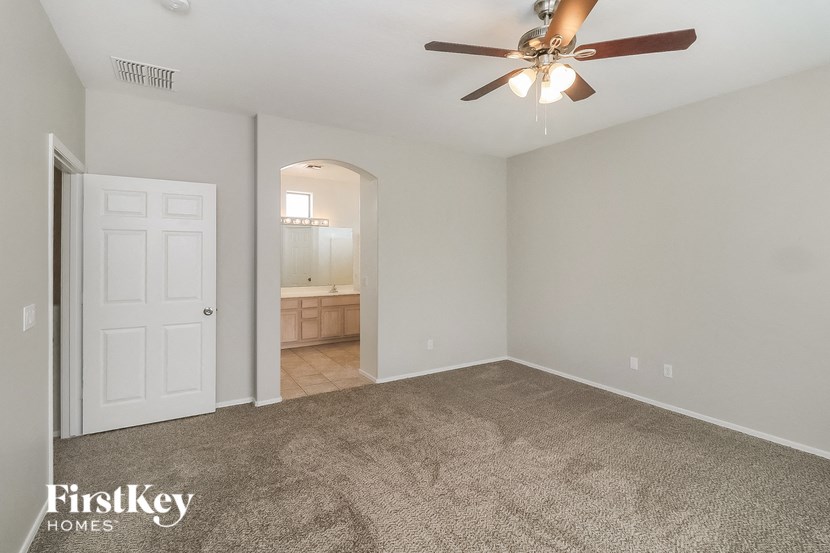an empty living room with a ceiling fan and a door to a bathroom