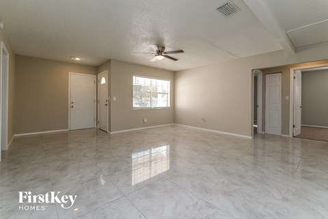 A spacious room with a ceiling fan and a large window.