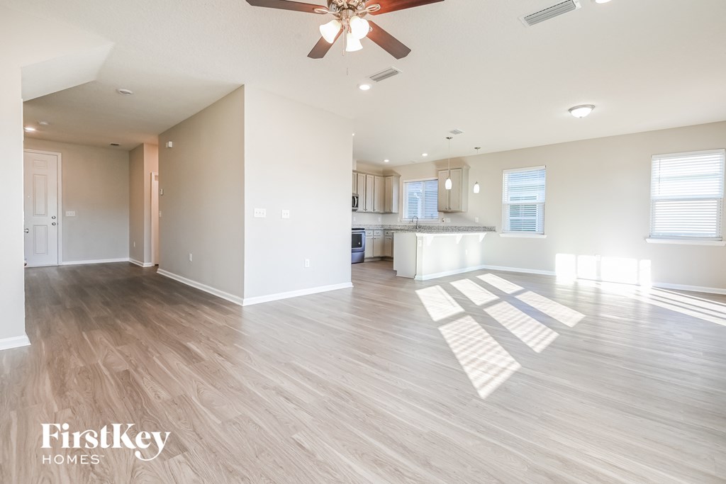 A spacious room with a ceiling fan and wooden flooring.
