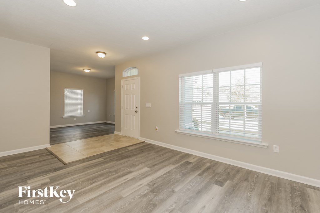 the living room and dining room of a house with wood floors and a white door