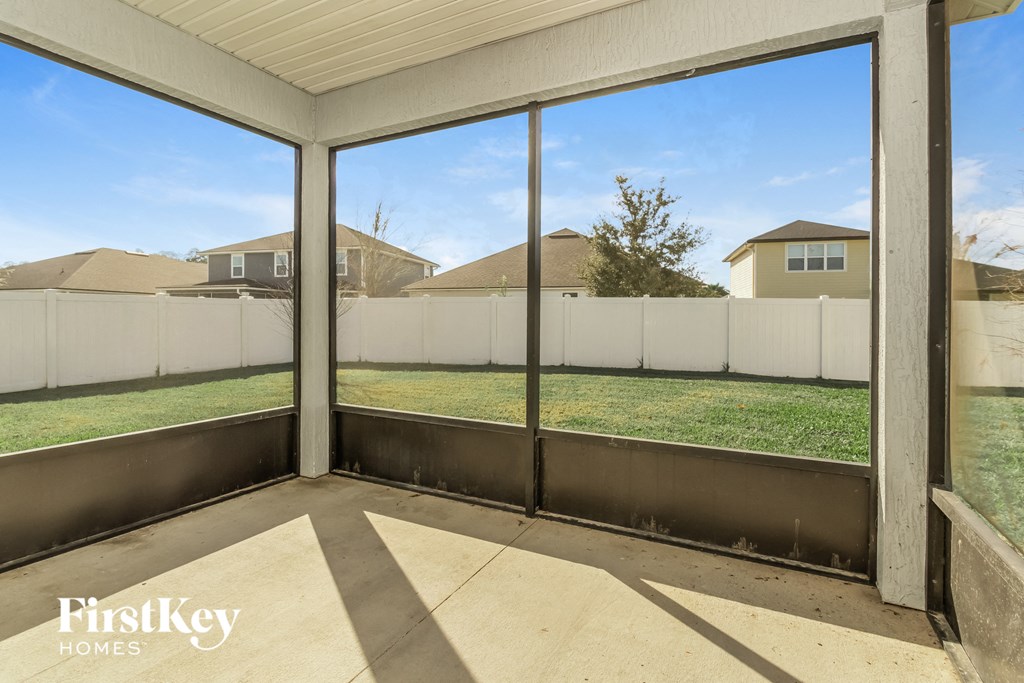 the view from the screened in porch of a backyard with a fence and grass