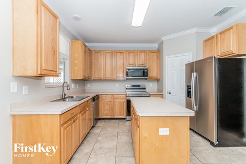 A kitchen with wooden cabinets and a black refrigerator.