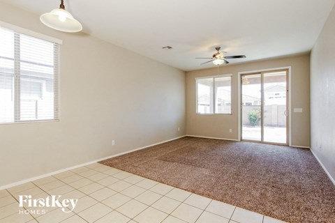an empty living room with a rug and a ceiling fan
