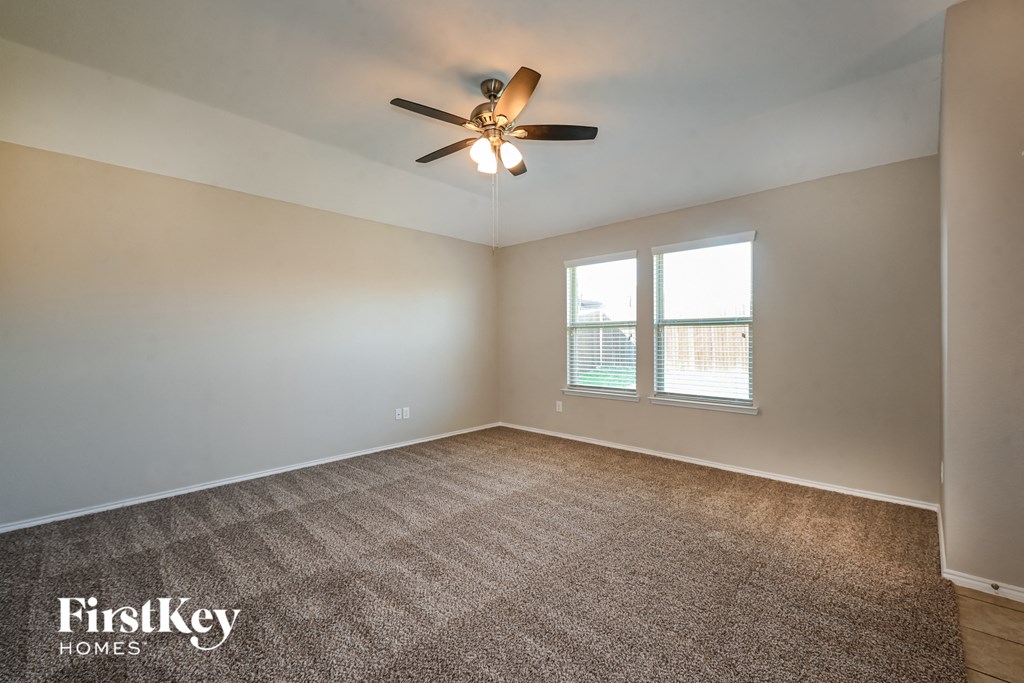 an empty living room with a ceiling fan and a window
