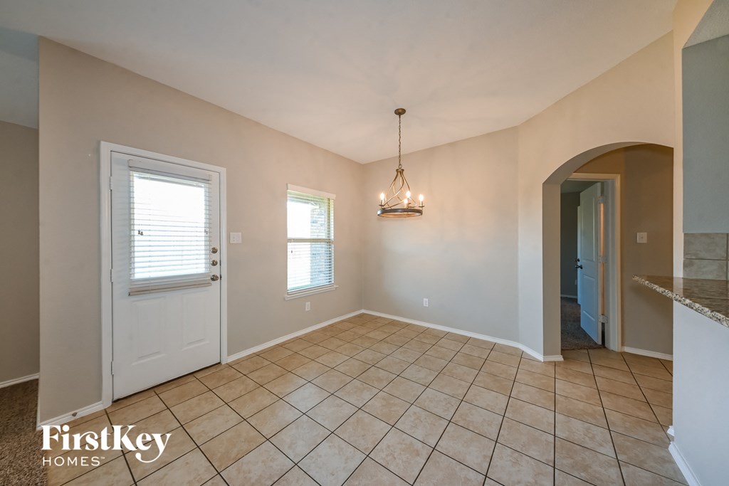 an empty dining room with tile flooring and a white door