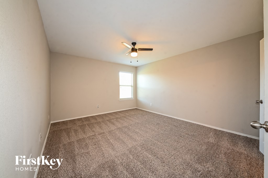 the living room of an empty house with carpet and a ceiling fan