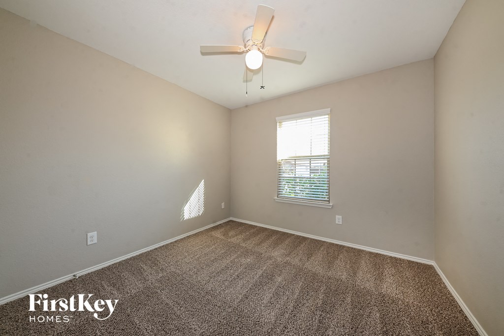an empty room with a ceiling fan and a window