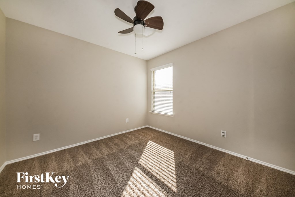 the living room is spacious and has a ceiling fan